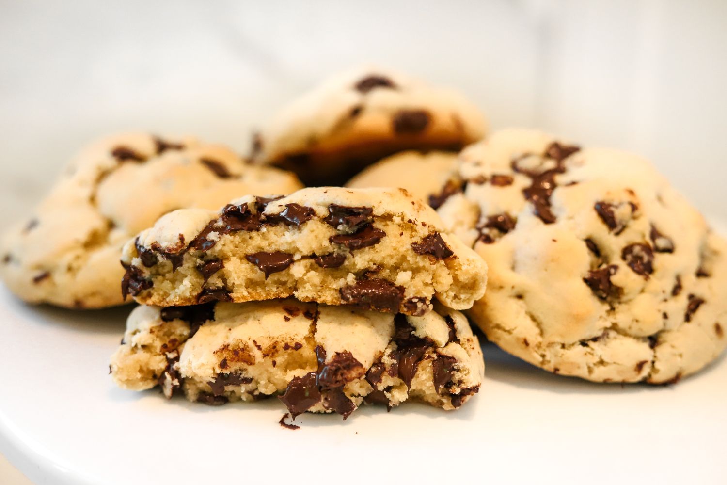 Illustrative chocolate chip cookies, stacked with a broken cookie showing the soft center